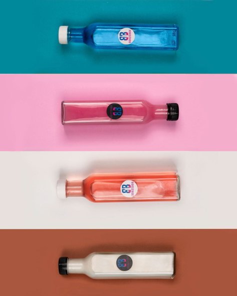 Four cocktail bottles with different colors of liquids on different colored backgrounds