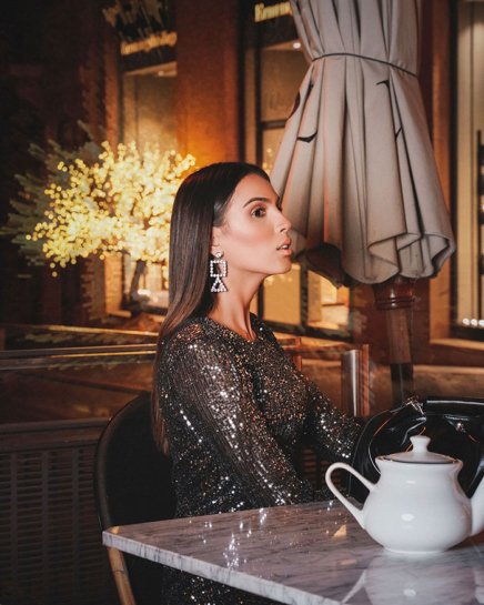 Young Woman Model Wearing a dark Sparkly Dress sitting in a café