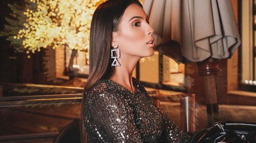 Young Woman Model Wearing a dark Sparkly Dress sitting in a café