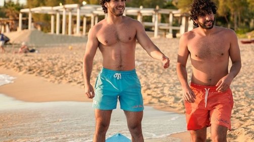 Two Young Men Models in the beach Wearing Blue and Orange Swimwear