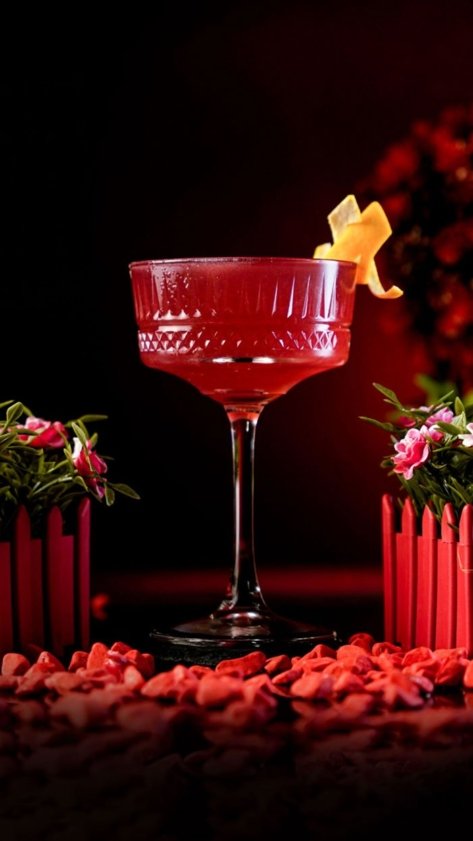 Red Detropolitan Cocktail inside Carved Coupe Glass around red background