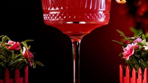 Red Detropolitan Cocktail inside Carved Coupe Glass around red background