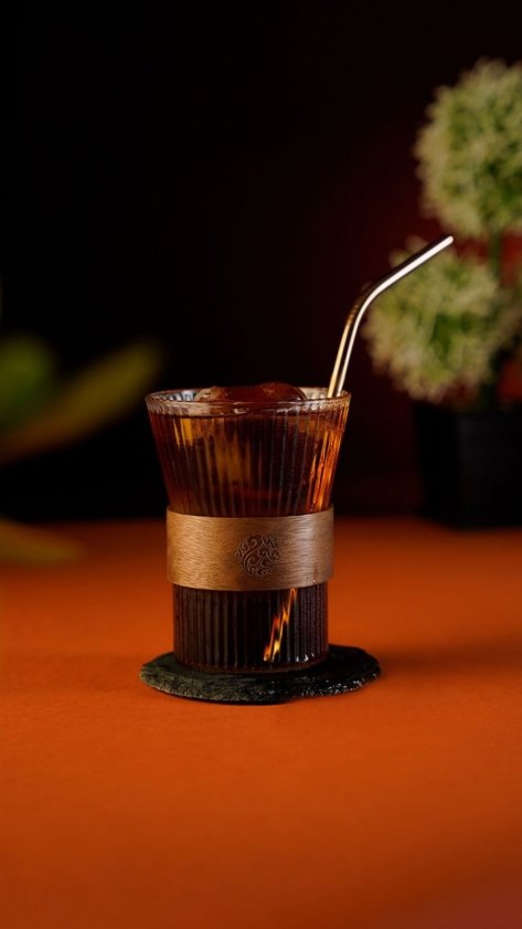 Coffee Cocktail inside a Striped monk glass on an orange background