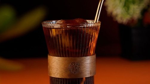 Coffee Cocktail inside a Striped monk glass on an orange background