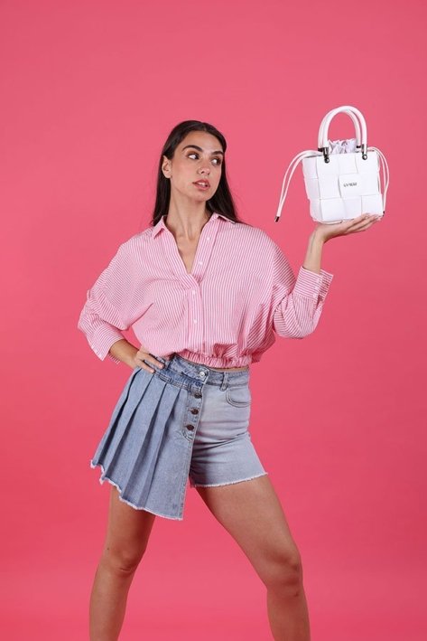Young Woman Model wearing a pink shirt and jeans skrit and carrying a white bag