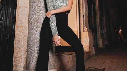 Young Woman Model Wearing Grey and Black Outfit laying on a brick wall