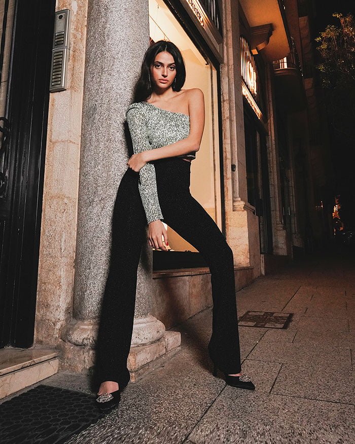 Young Woman Model Wearing Grey and Black Outfit laying on a brick wall